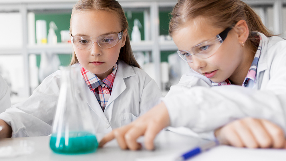 Two students working on chemistry experiment in school laboratory.