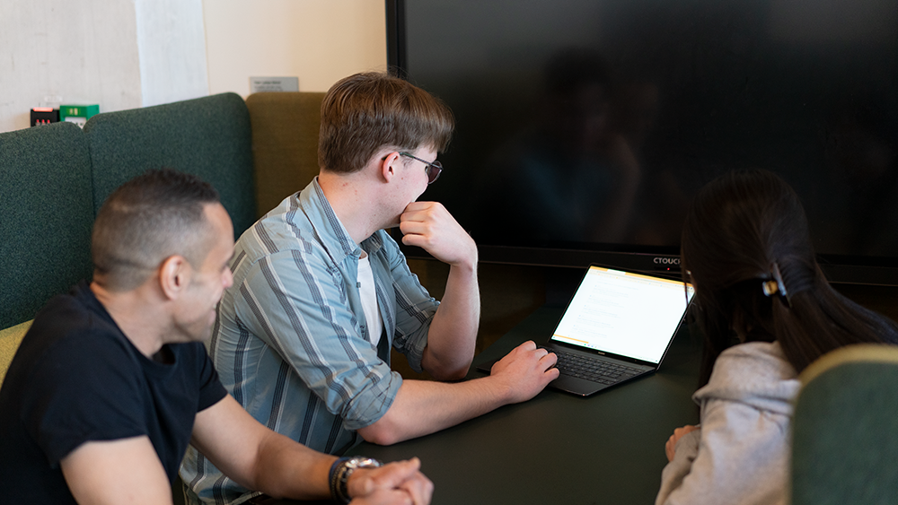 Studenter rundt et bord med laptop. Ilustrasjonsfoto. 