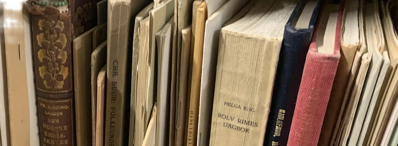Gamle bøker og dokumenter i bokhylle. Blant annet vises pedagogiske klassikere fra Helga Eng.
