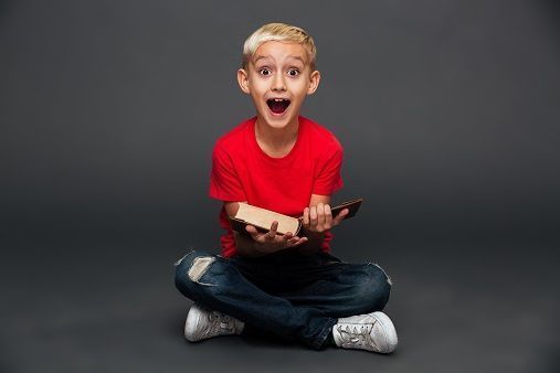 Smiling boy with a red t-shirt holding a book