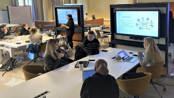 Grupper med studenter samarbeider foran skjermer