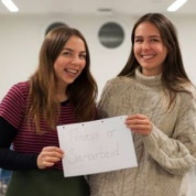 To studenter holder opp en plakat med teksten praksis er samarbeid