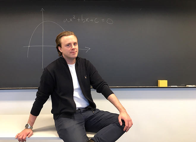 Alexander Jonas Viktor Selling sitting in the classroom in front of a blackboard with a graph drawn on it