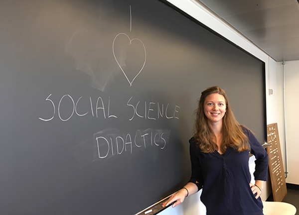 Nora Elise Hesby Mathé standing in front of black board where she has written: I love social science didactics